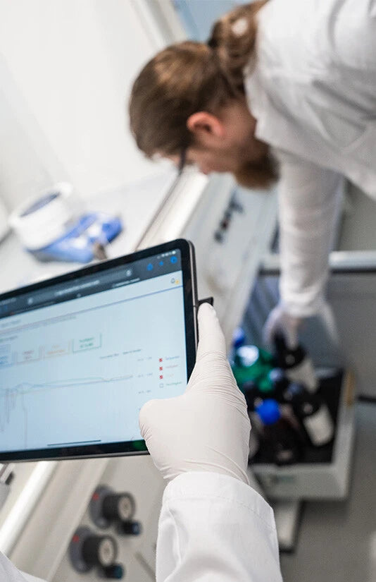 Mitarbeiterin im Labor prüft Daten am Tablet